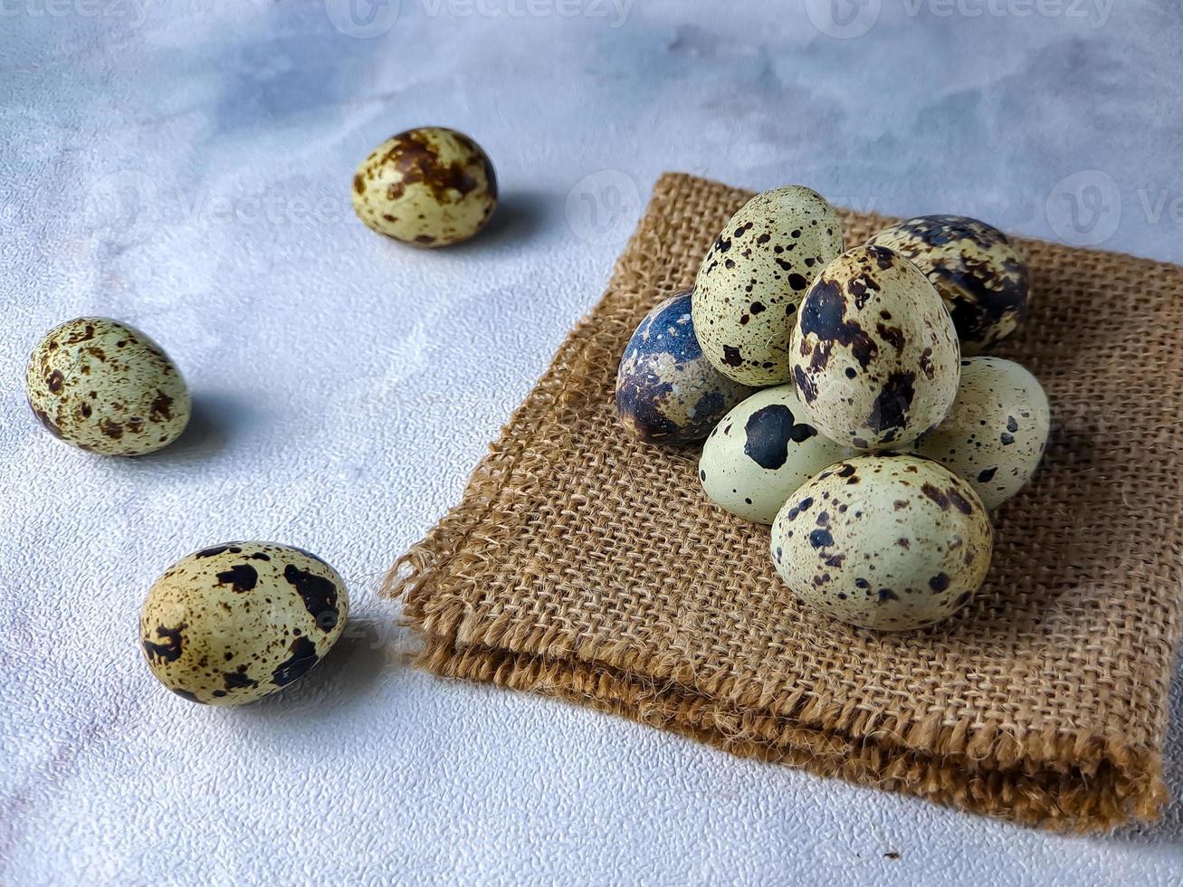 Quail eggs from quail, a collection of quail eggs on a wooden plate against a white wall background photo