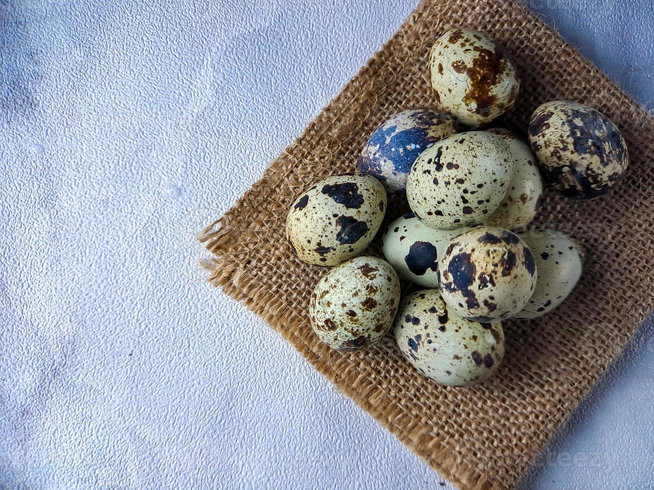 Quail eggs from quail, a collection of quail eggs on a wooden plate against a white wall background photo