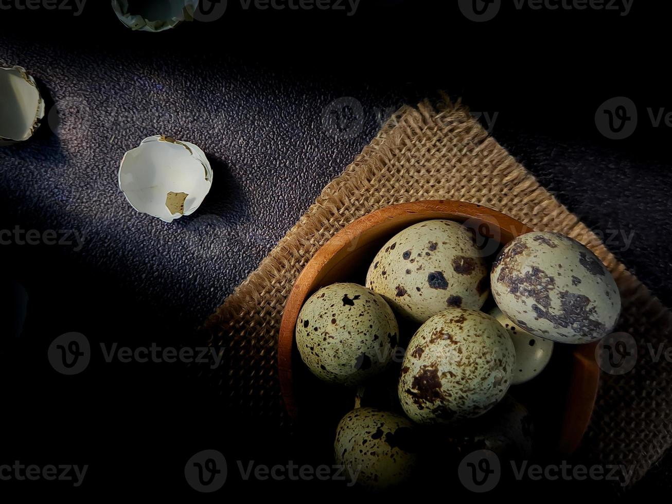 Quail eggs from quail, a collection of quail eggs on a wooden plate with a black sand background photo