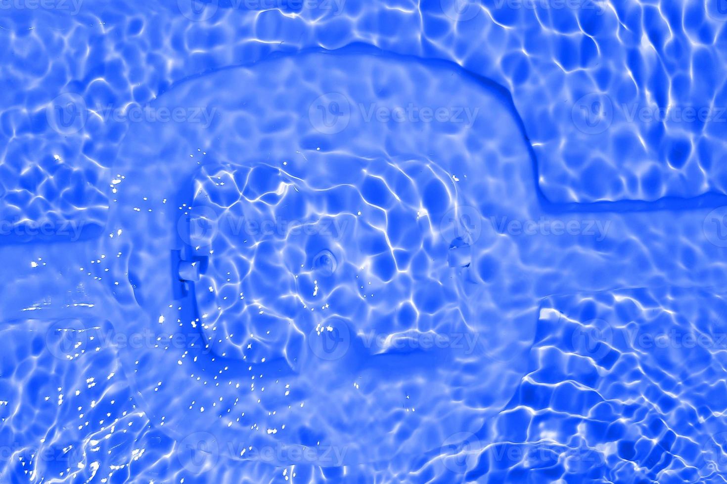 Defocus blurred transparent blue colored clear calm water surface texture with splashes and bubbles. Trendy abstract nature background. Water waves in sunlight with copy space. Blue watercolor shining photo