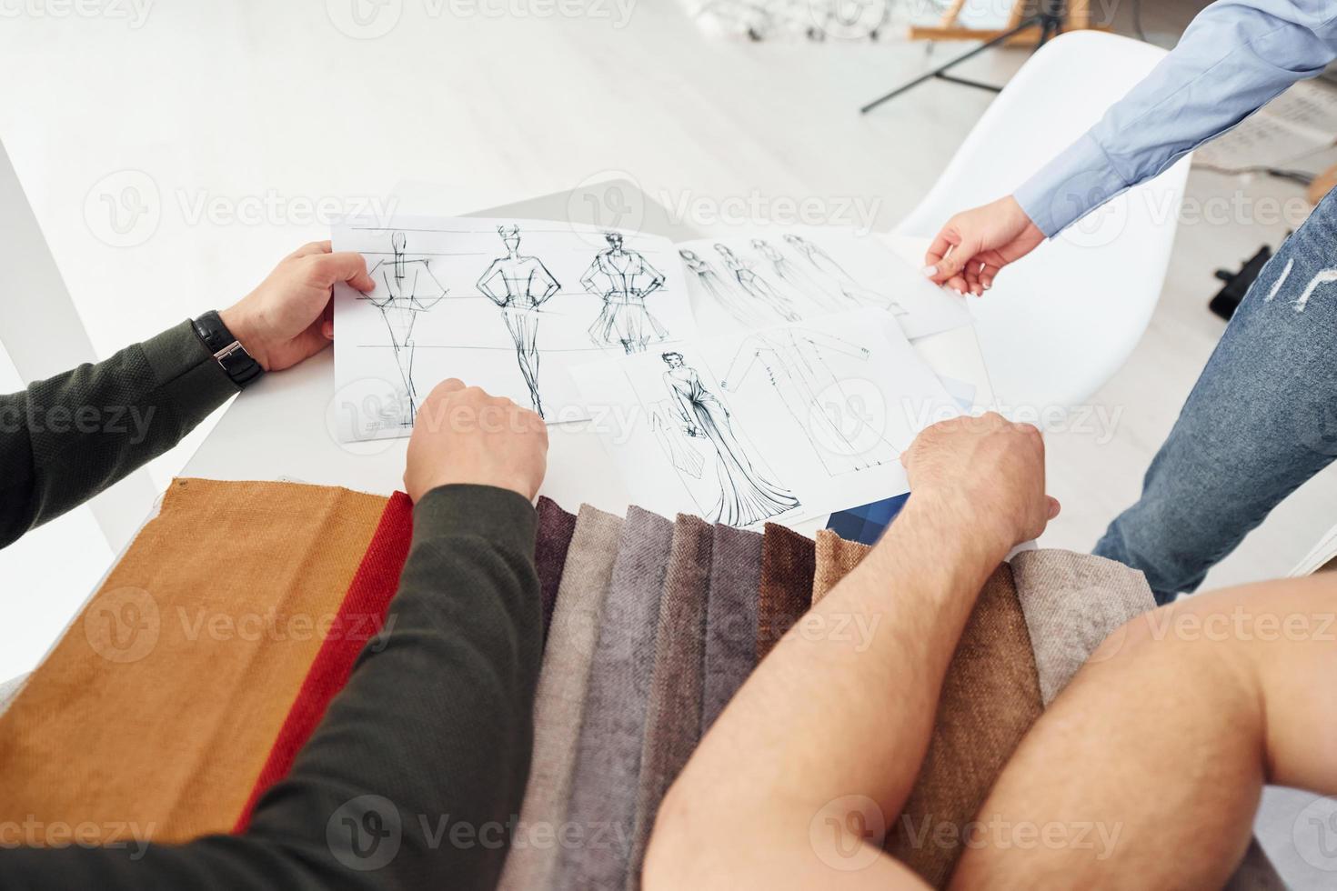 negocio de telas y moda. tres personas trabajan en la oficina sentándose junto a la mesa foto