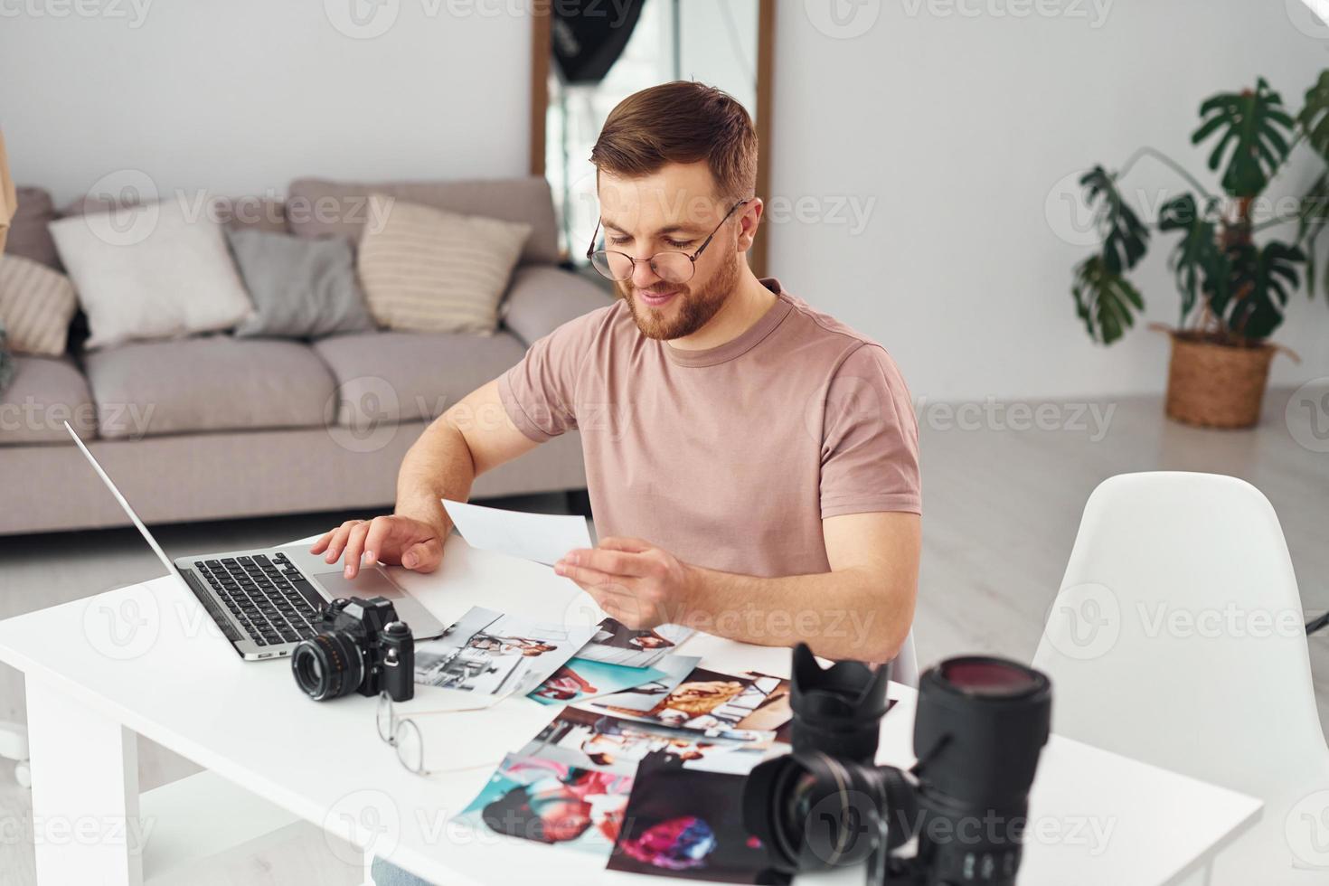 Photographer in casual clothes is working indoors at daytime photo