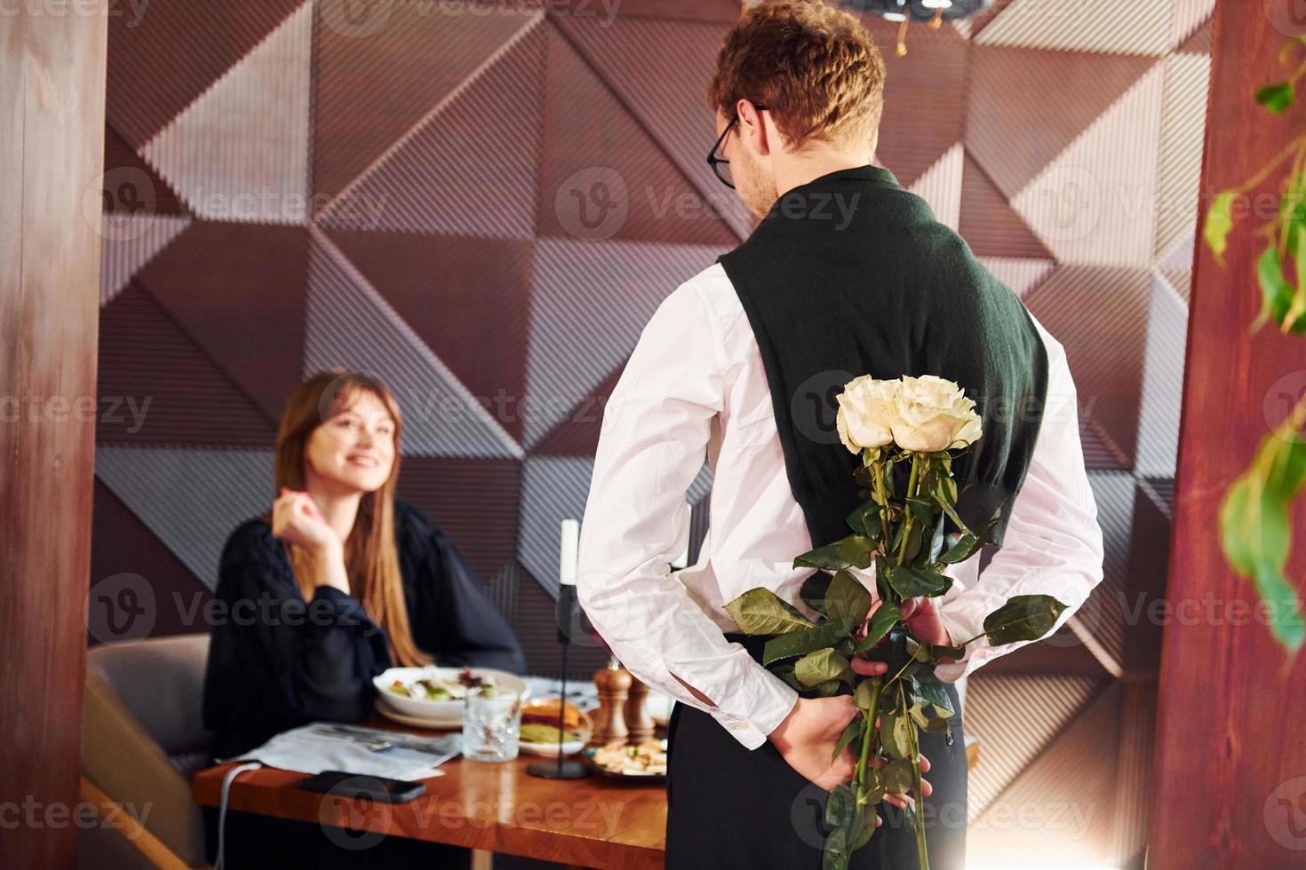 Waiter gives flowers to a woman. Indoors of new modern luxury restaurant photo