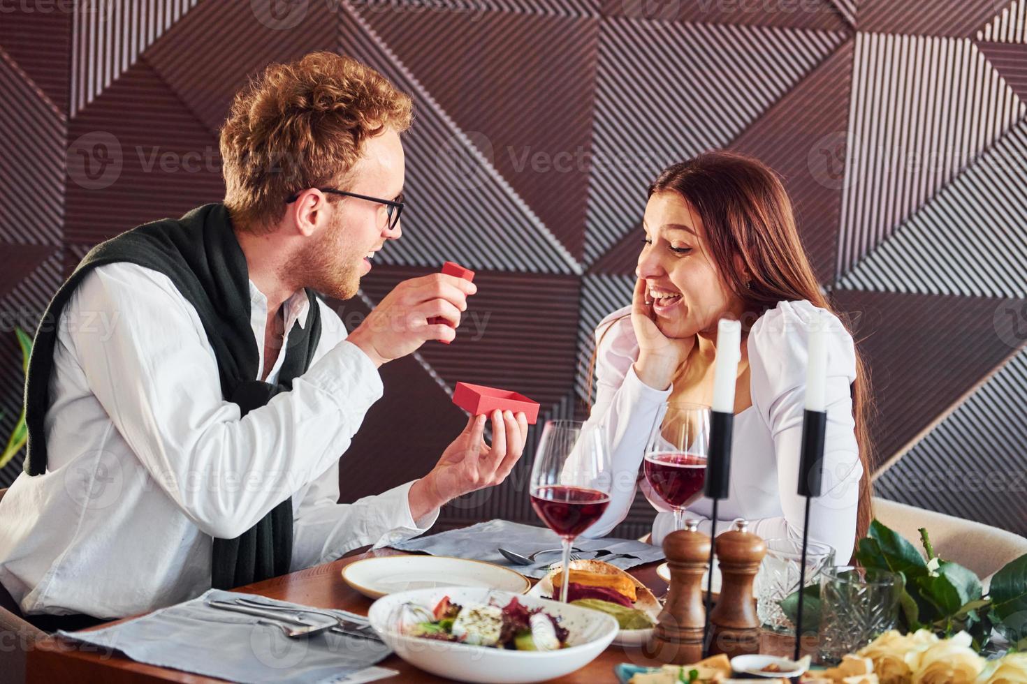 Young guy makes proposal to a woman. Indoors of new modern luxury restaurant photo