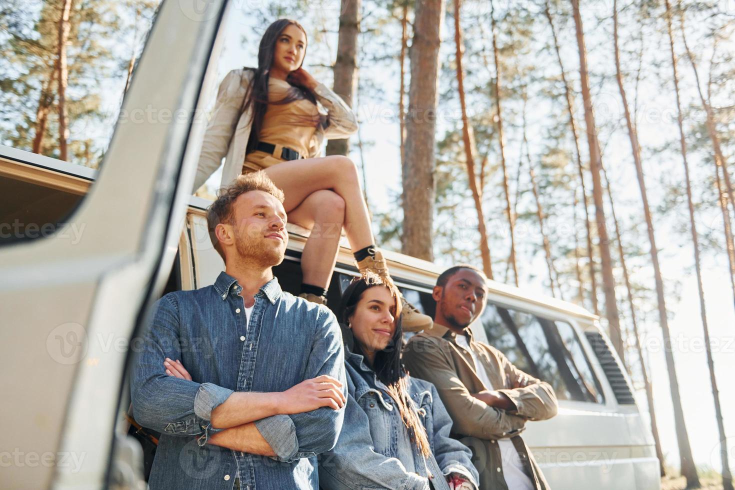 Destination place. Group of young people is traveling together in the forest at daytime photo