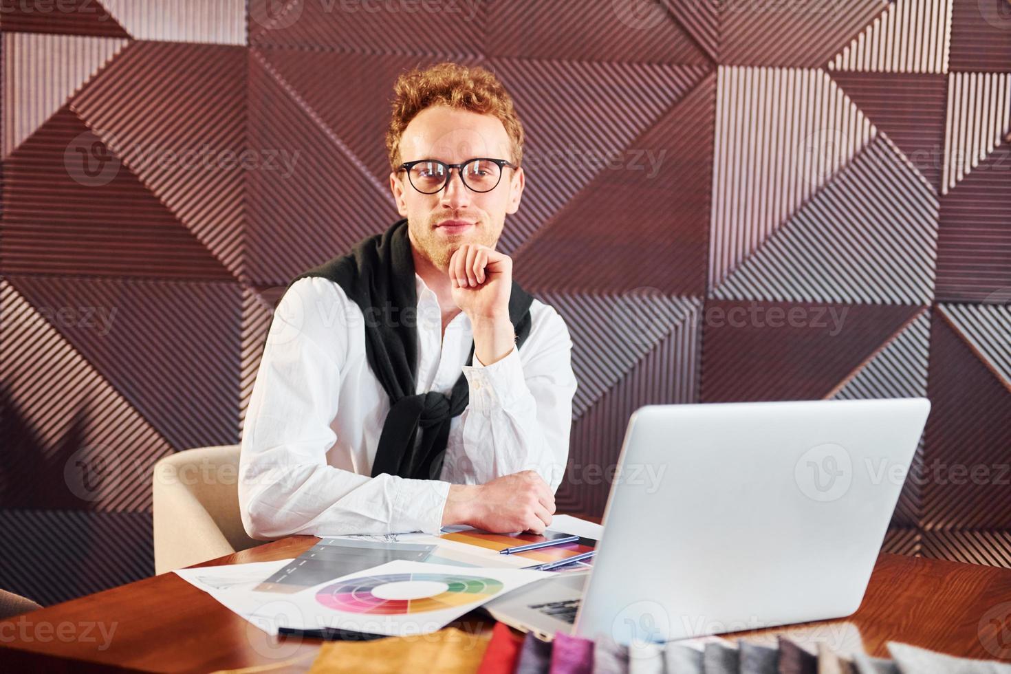 Man sits by table with laptop. Indoors of new modern luxury restaurant photo