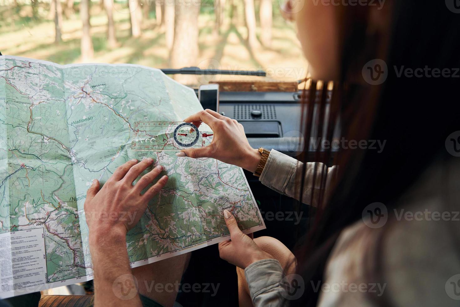 Looking for location by using map. Group of young people is traveling together in the forest at daytime photo