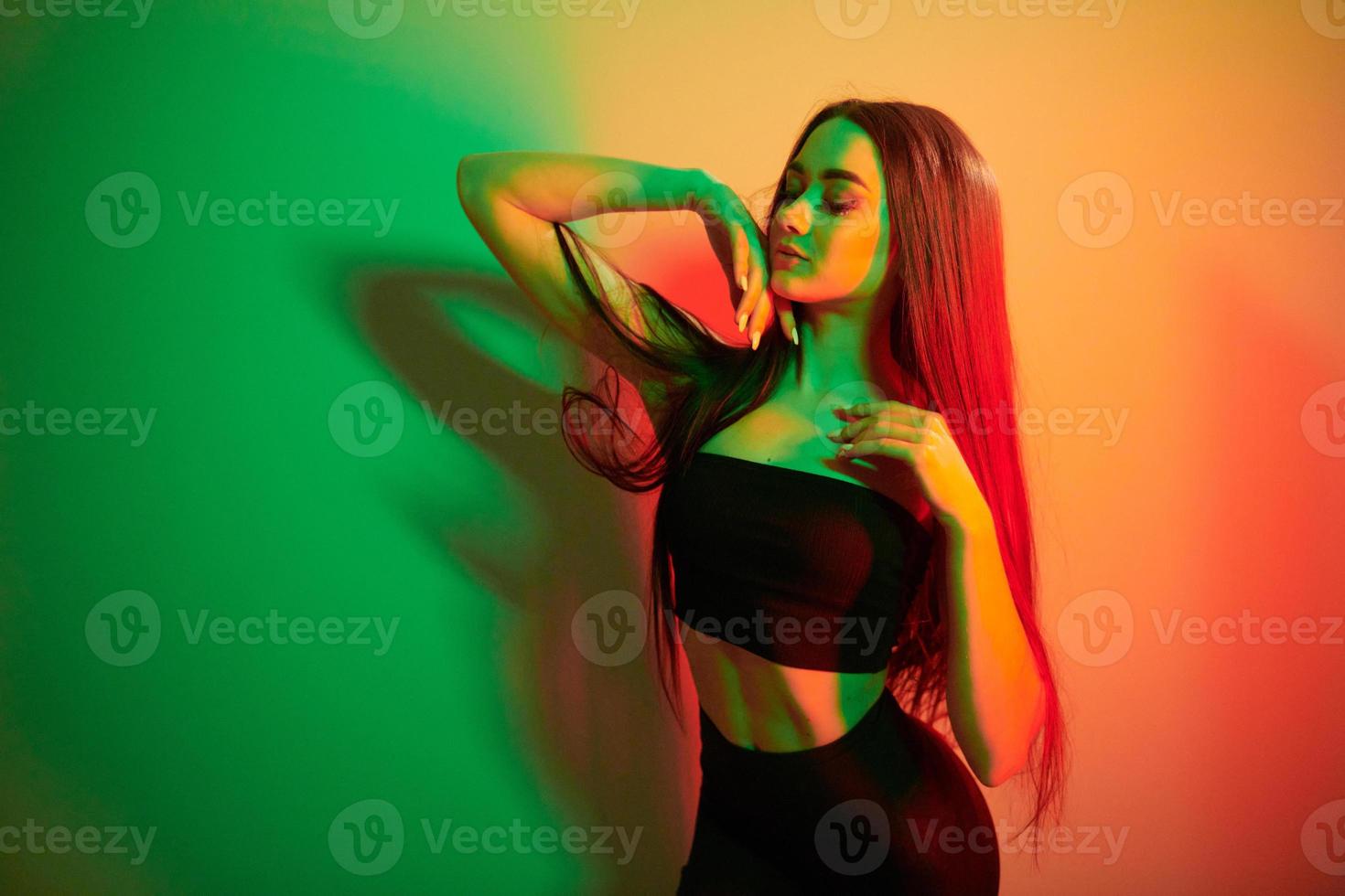 colores verde y rojo. joven de moda parada en el estudio con luz de neón foto