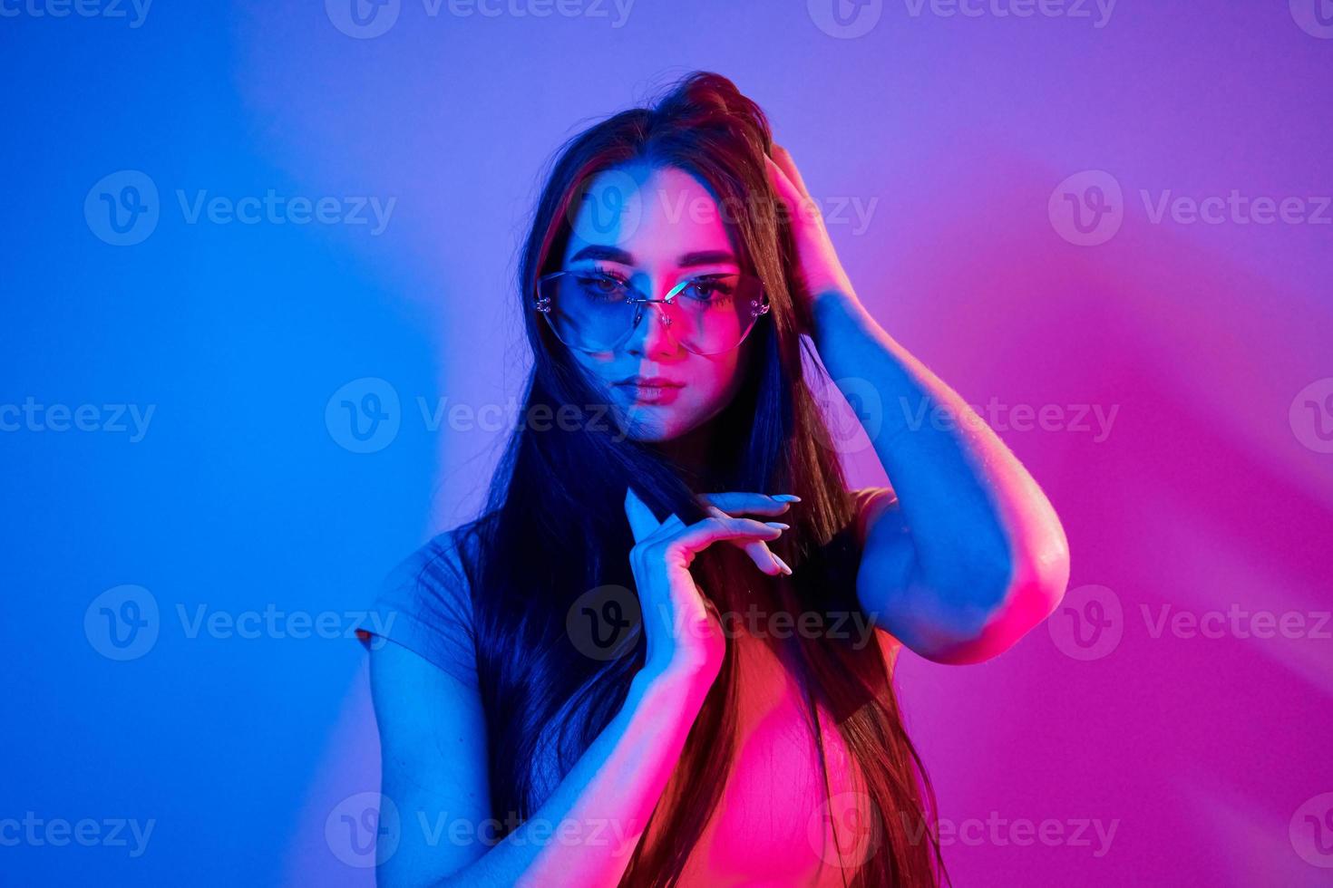 pelo largo de color castaño. joven de moda parada en el estudio con luz de neón foto