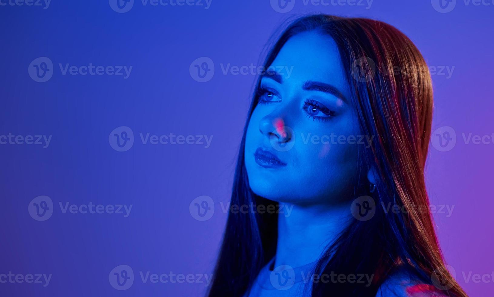 Fashionable young woman standing in the studio with neon light photo