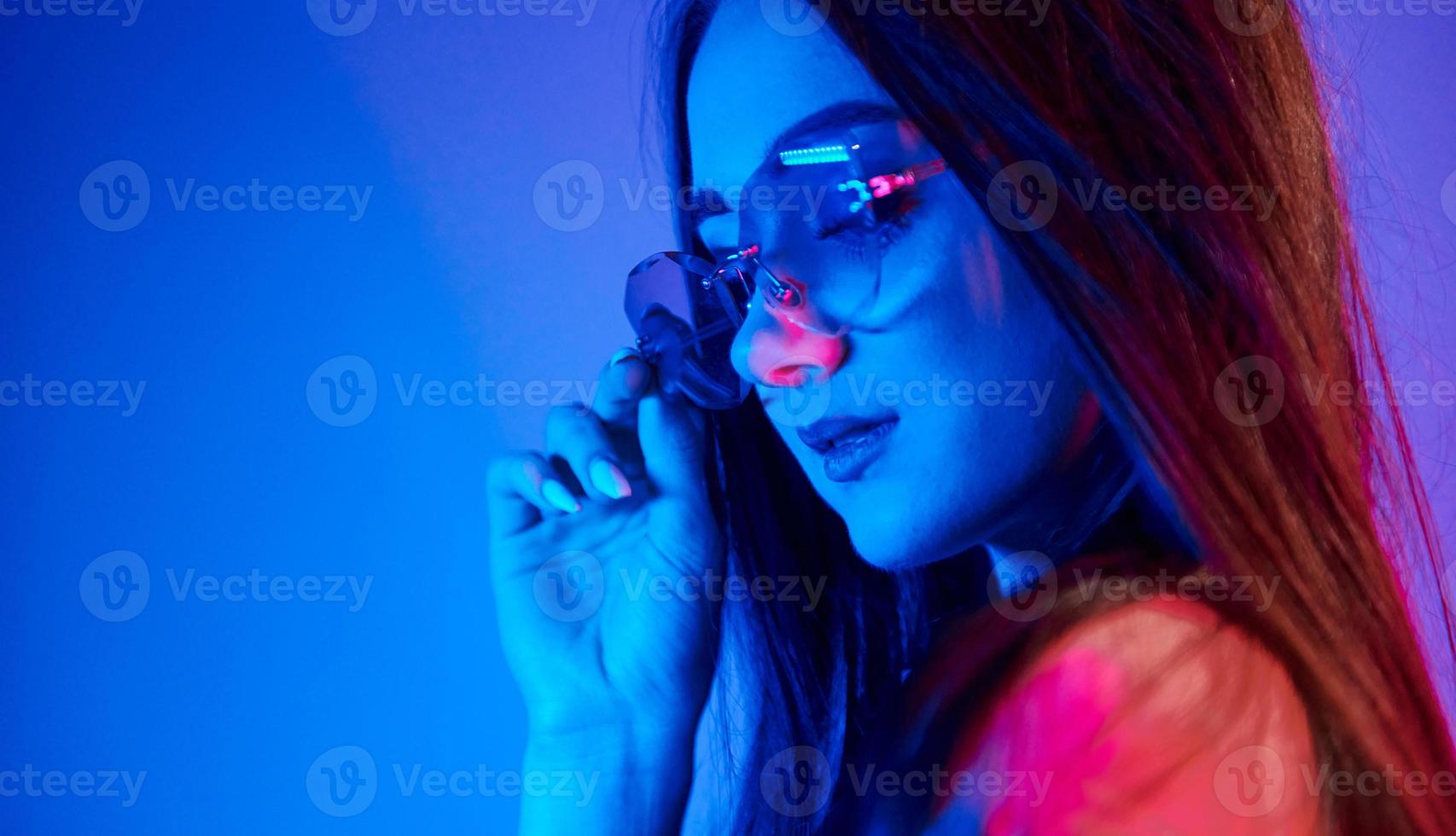 Fashionable young woman standing in the studio with neon light photo