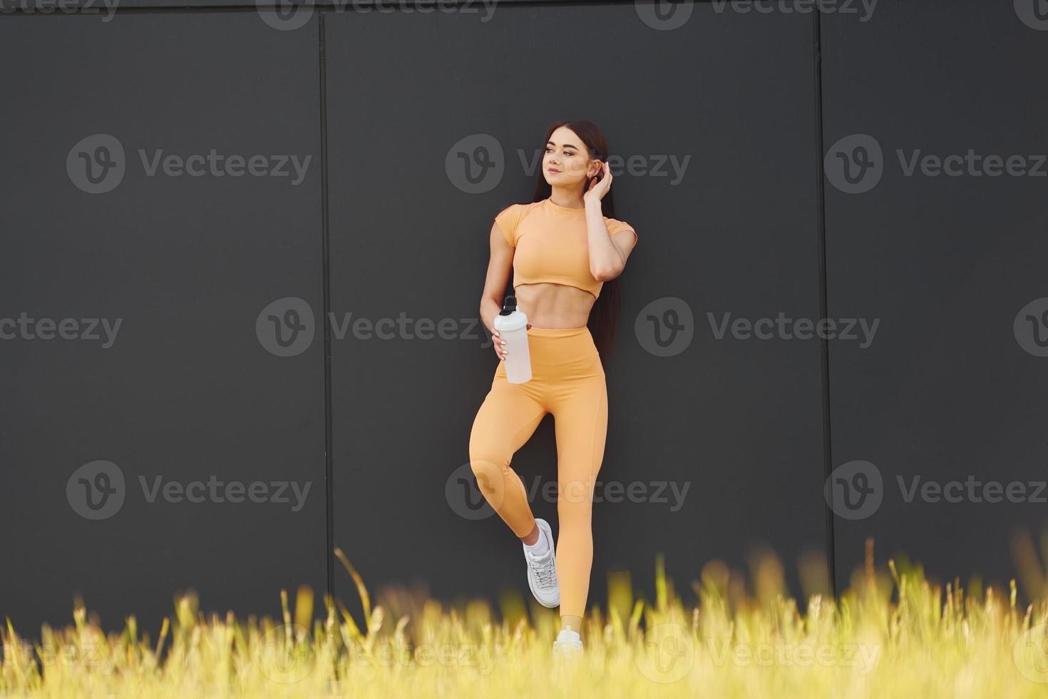 With bottle of water. Young woman in sportswear have fitness session outdoors photo