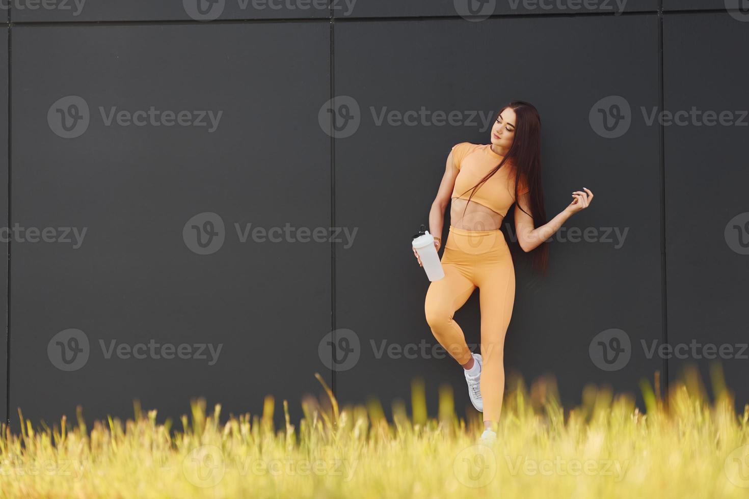 With bottle of water. Young woman in sportswear have fitness session outdoors photo