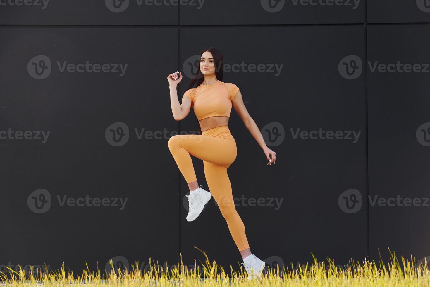 Training against black background. Young woman in sportswear have fitness session outdoors photo