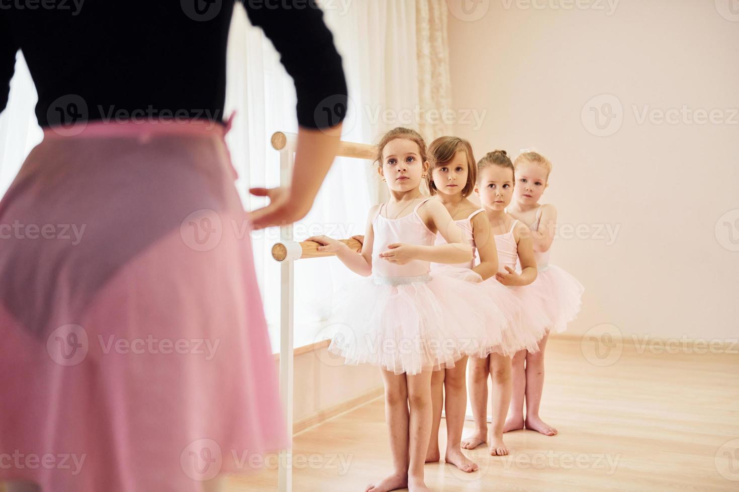 entrenador enseña a los niños. pequeñas bailarinas preparándose para la actuación practicando movimientos de baile foto