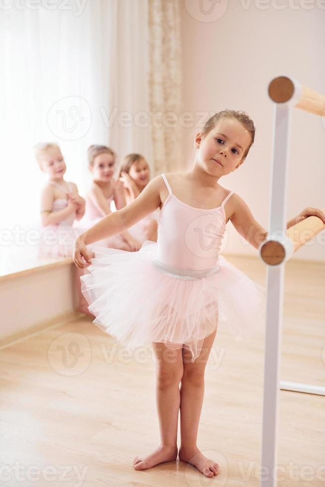 Leaning on the wooden stand. Little ballerinas preparing for performance photo