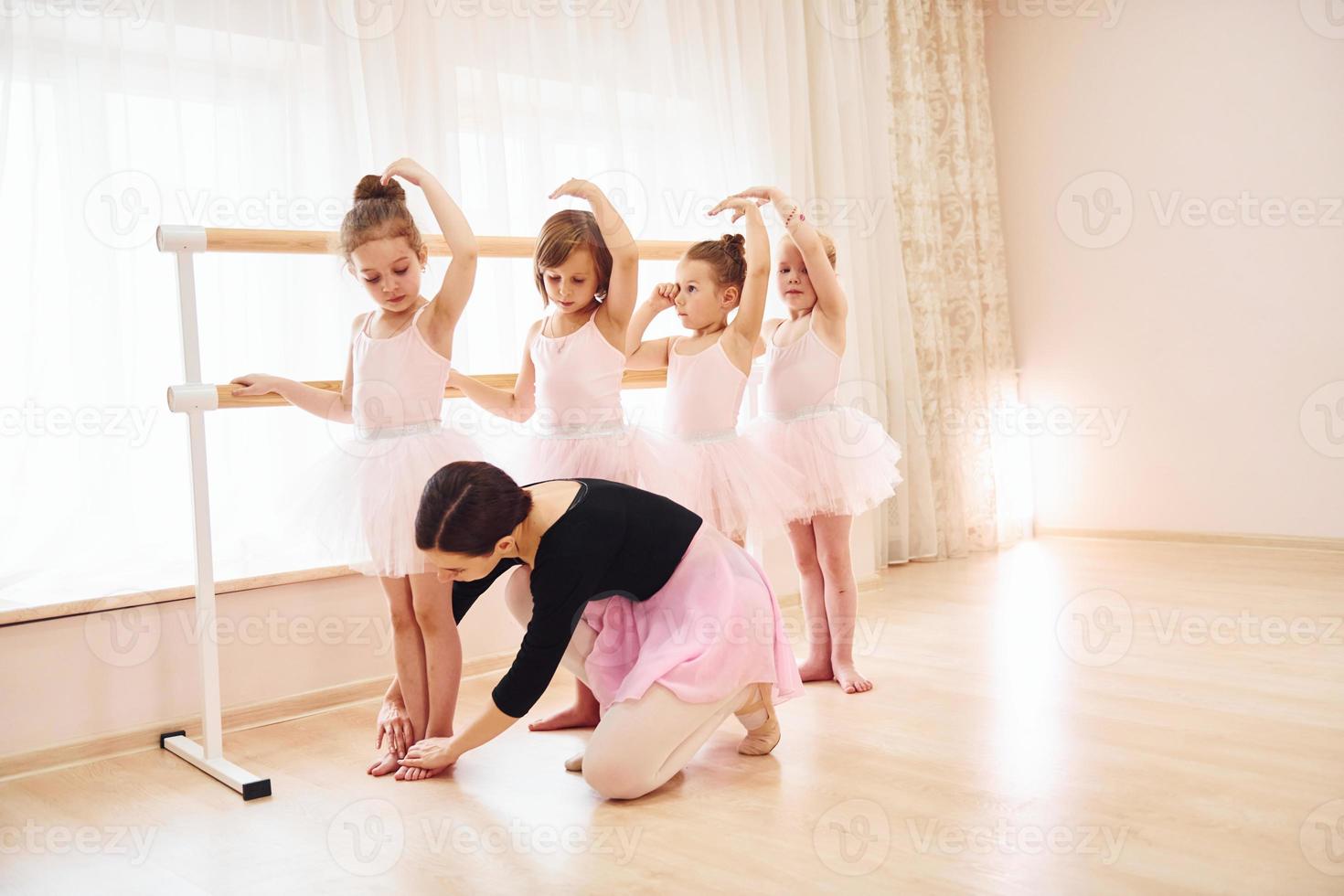 Working with coach. Little ballerinas preparing for performance by practicing dance moves photo