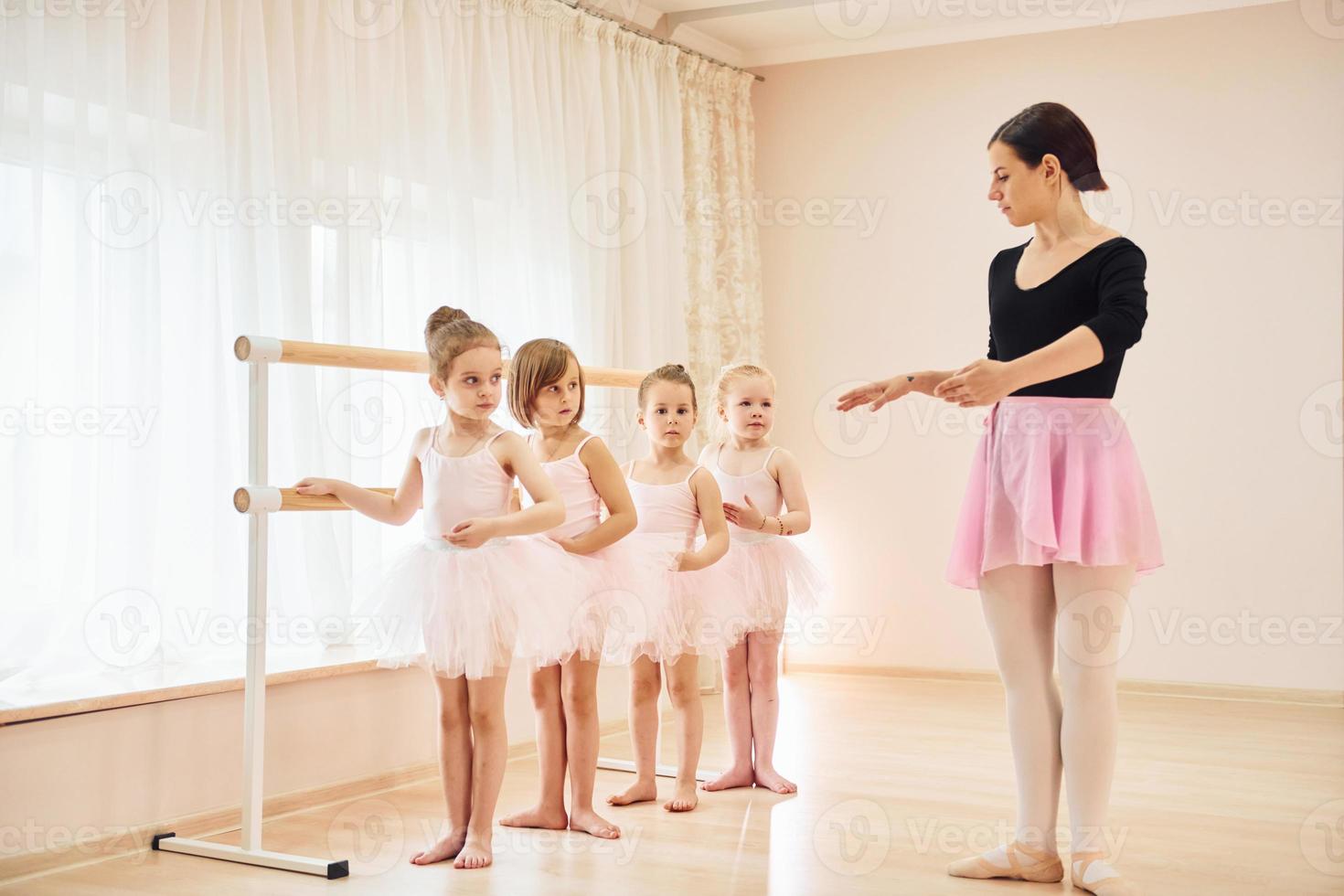 Coach teaches children. Little ballerinas preparing for performance by practicing dance moves photo