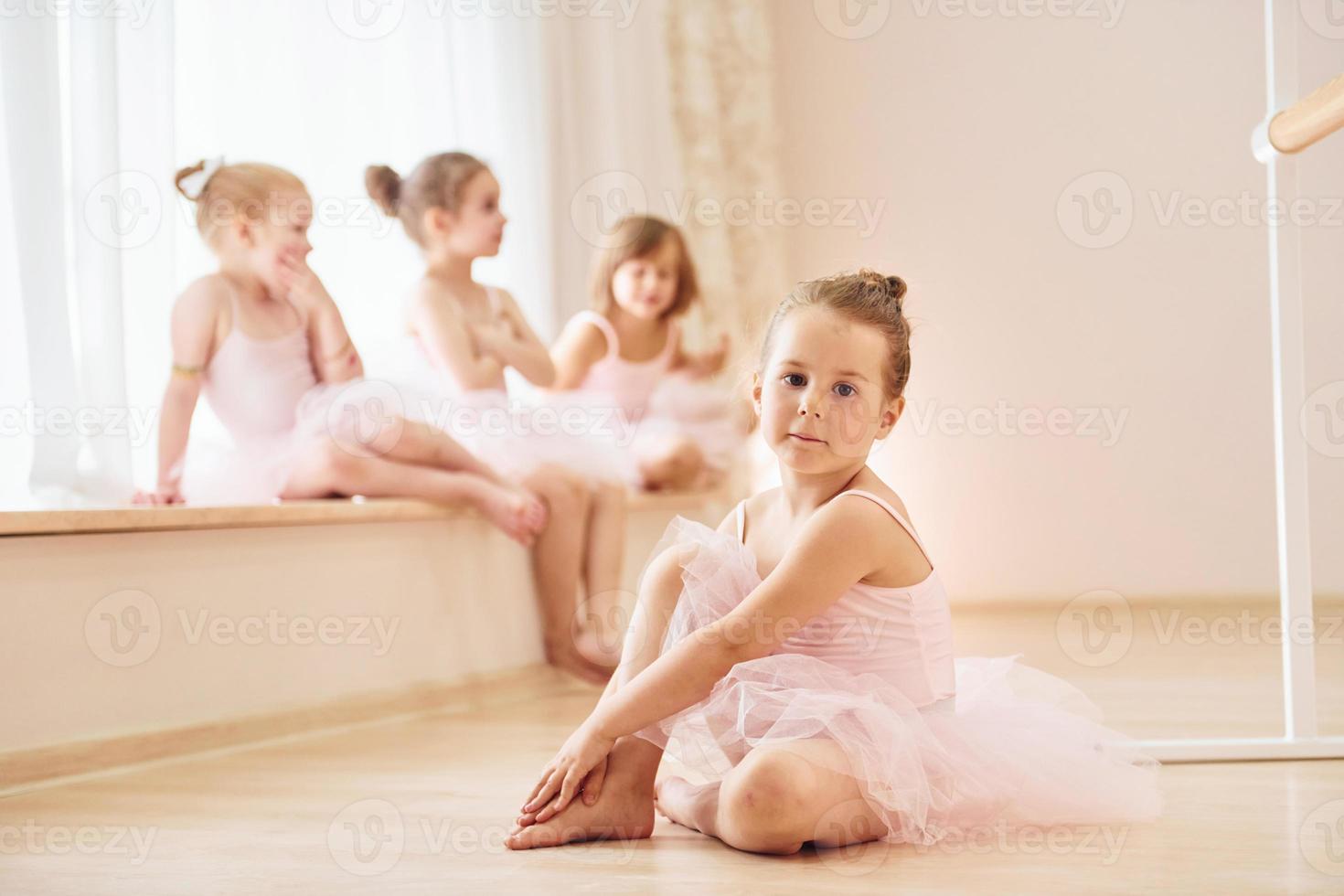 Girls sits on windowsill and on the floor. Little ballerinas preparing for performance photo