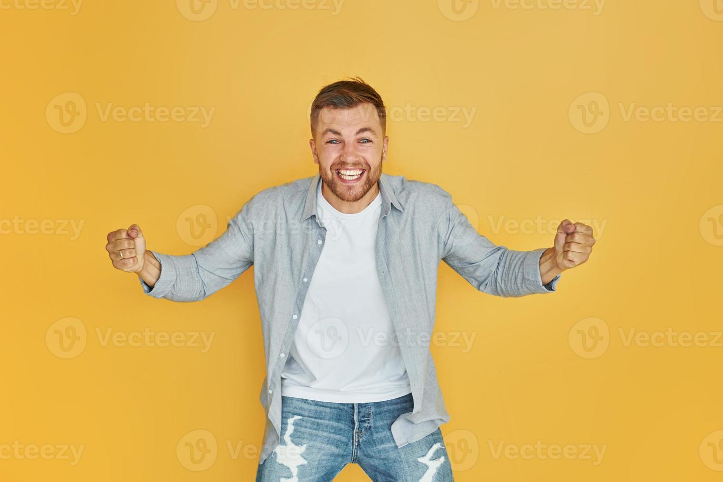 Feels good. Young man in casual clothes standing indoors in the studio photo