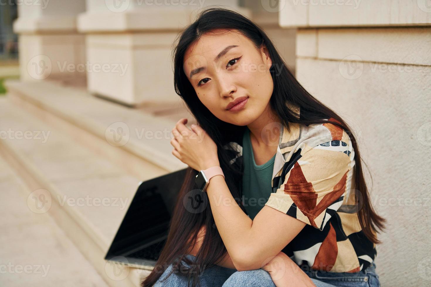 sentado y relajado. joven asiática está al aire libre durante el día foto