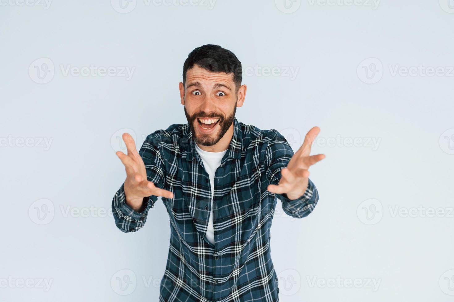 In in a plaid shirt. Young man in casual clothes standing indoors in the studio photo