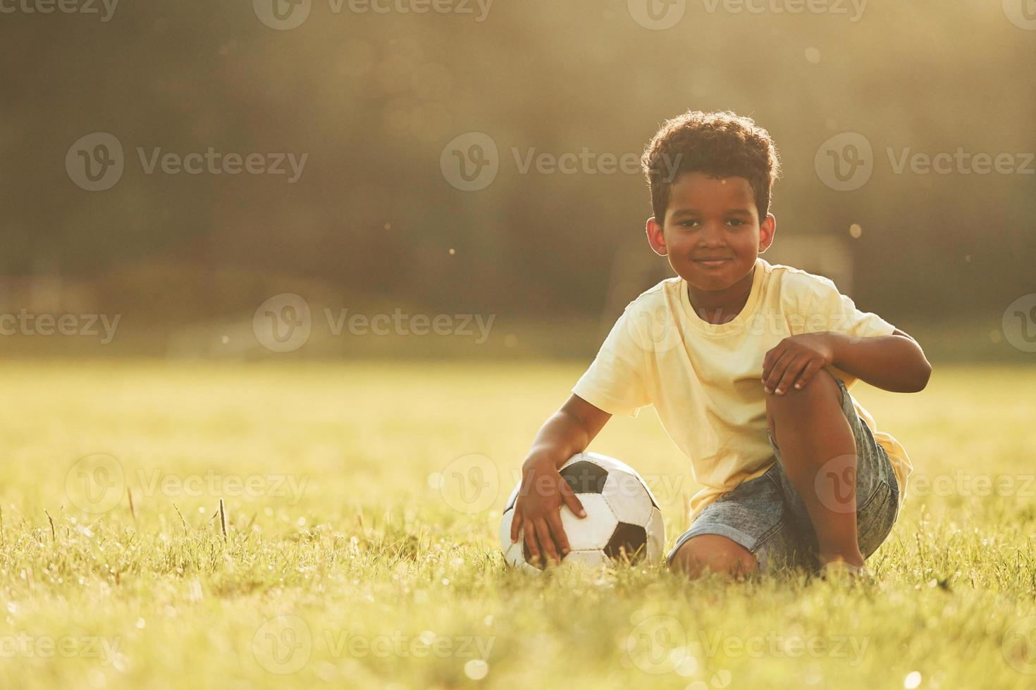 Illuminated by sunlight. African american kid have fun in the field at summer daytime photo