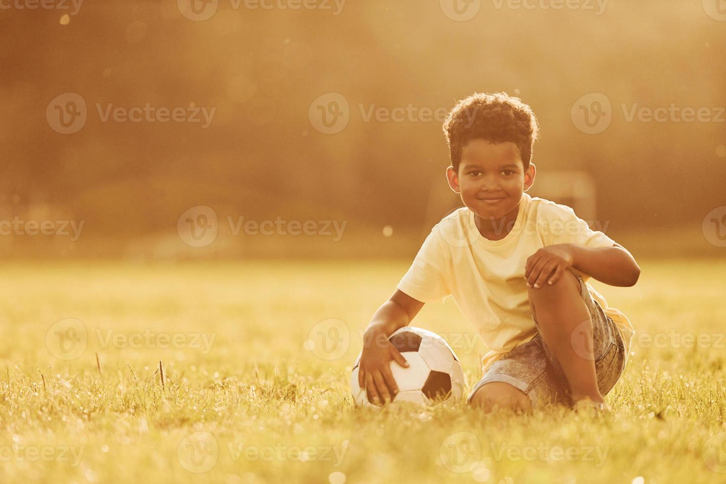 Illuminated by sunlight. African american kid have fun in the field at summer daytime photo