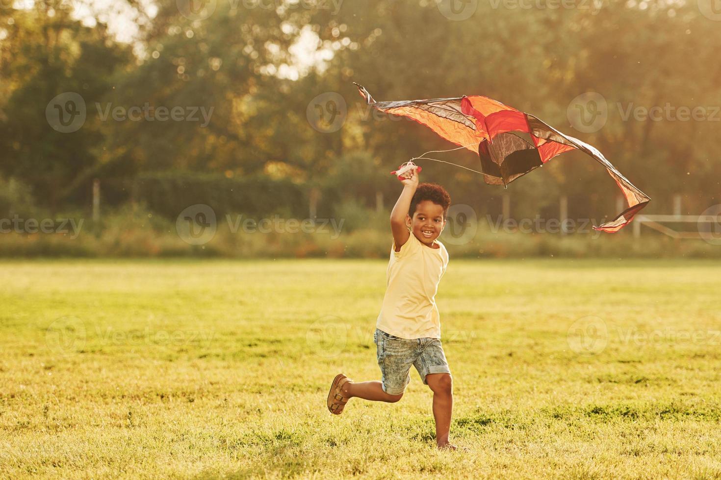 Red kite. African american kid have fun in the field at summer daytime photo