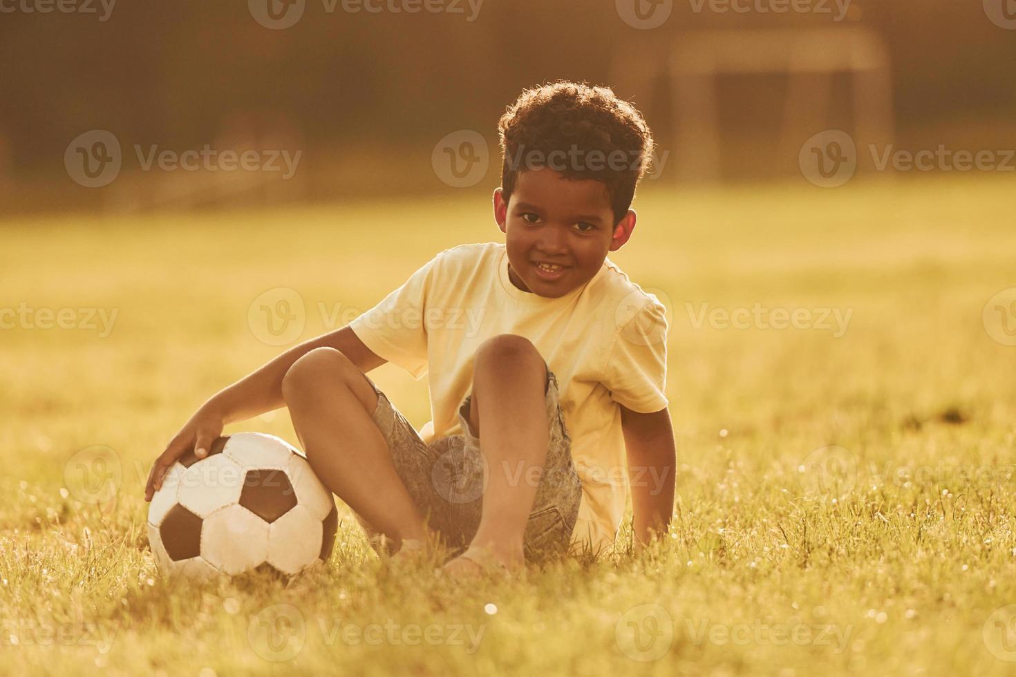 Beautiful sunshine. African american kid have fun in the field at summer daytime photo