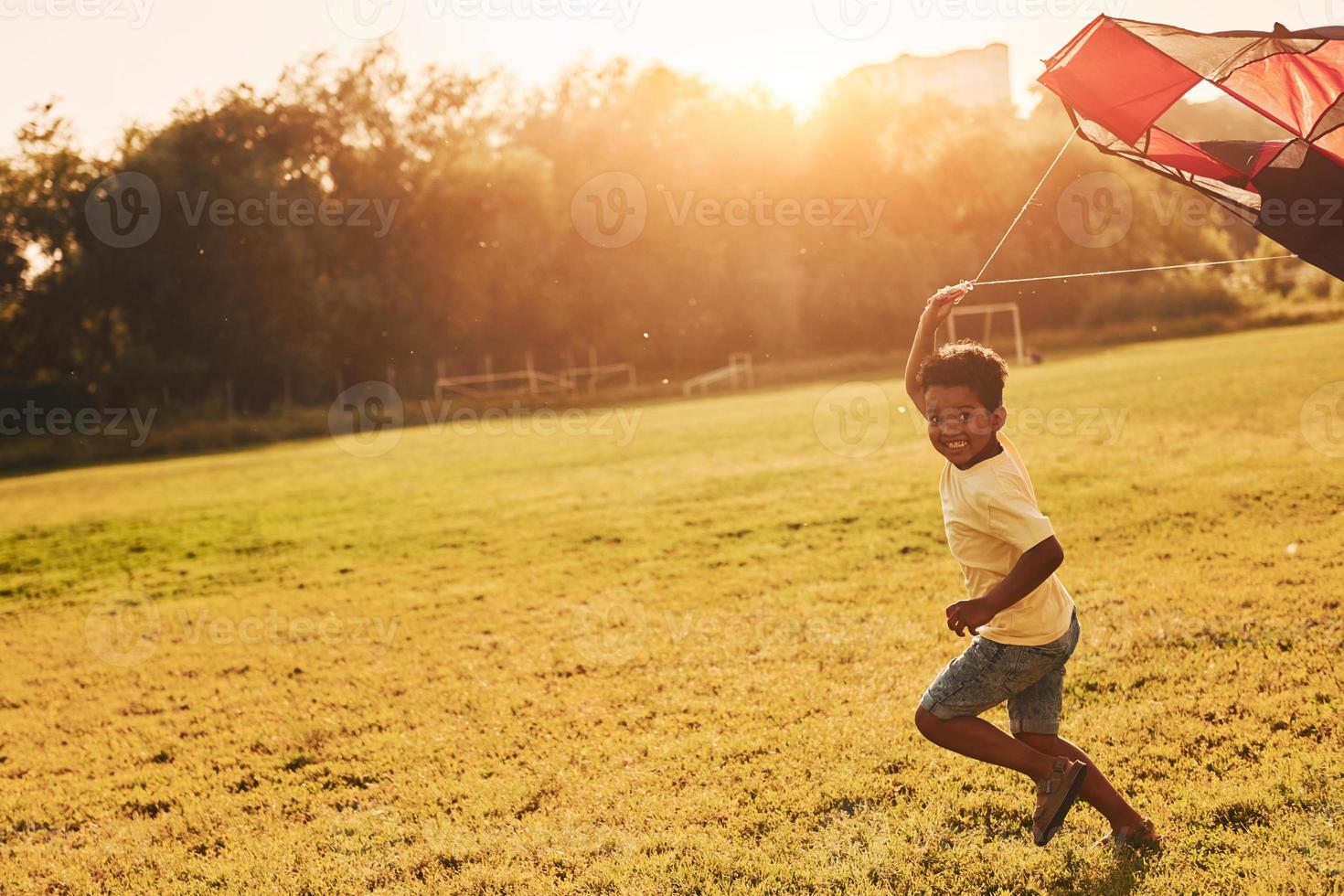 Playing with kite. African american kid have fun in the field at summer daytime photo