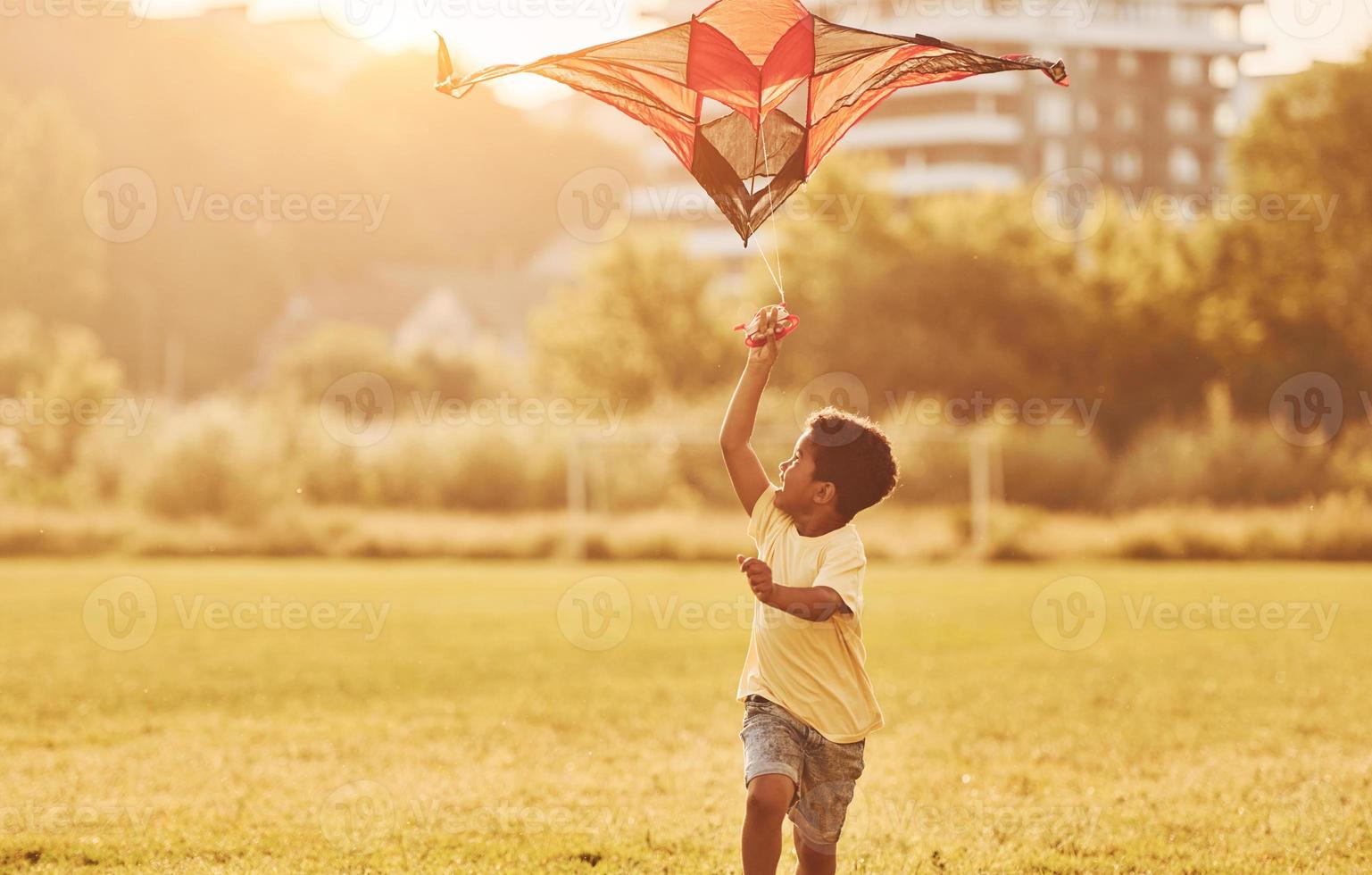 Red kite. African american kid have fun in the field at summer daytime photo