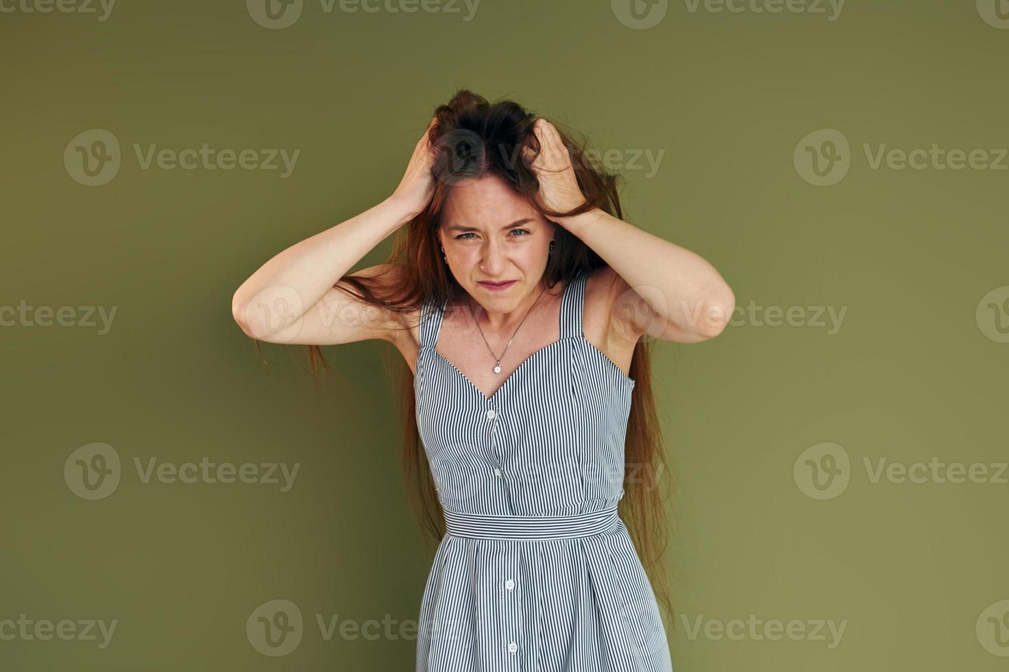 Demonstration of emotions. Young woman in casual clothes standing indoors in the studio photo