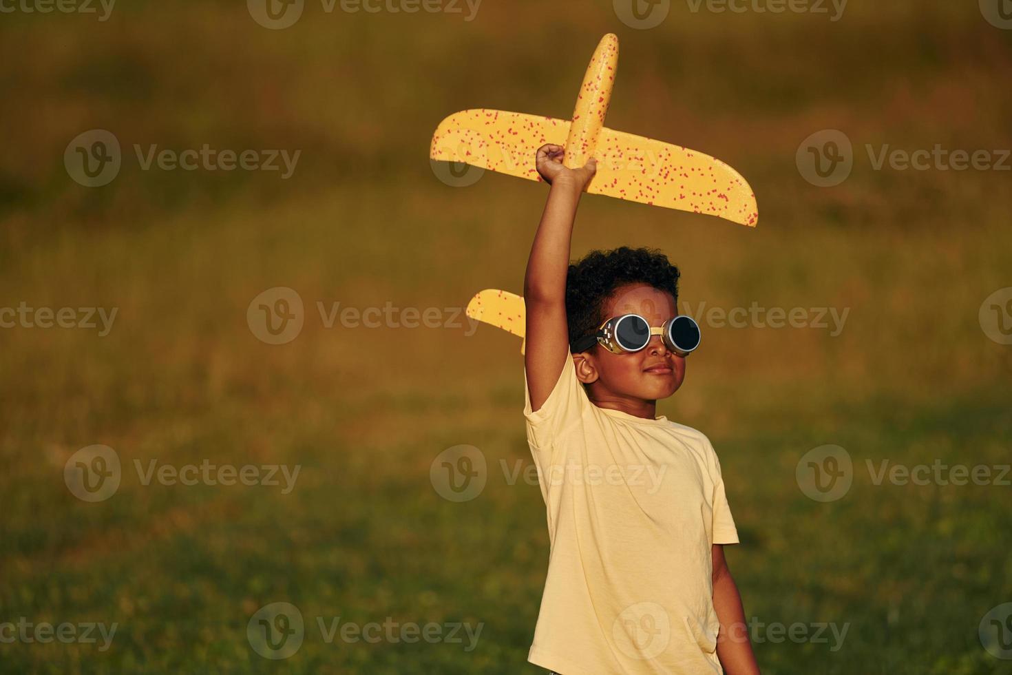 Retro style pilot sunglasses. African american kid have fun in the field at summer daytime photo