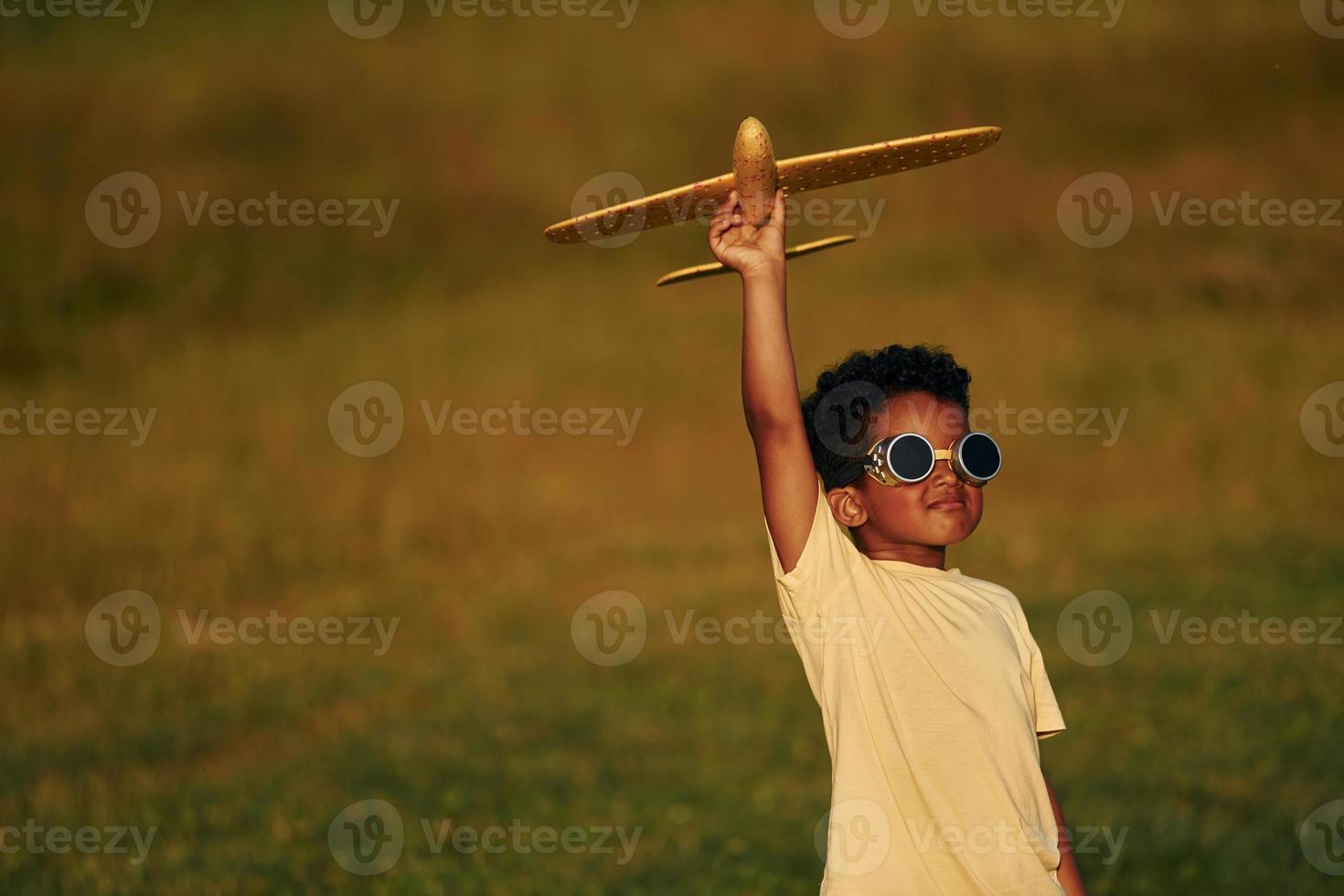 Retro style pilot sunglasses. African american kid have fun in the field at summer daytime photo