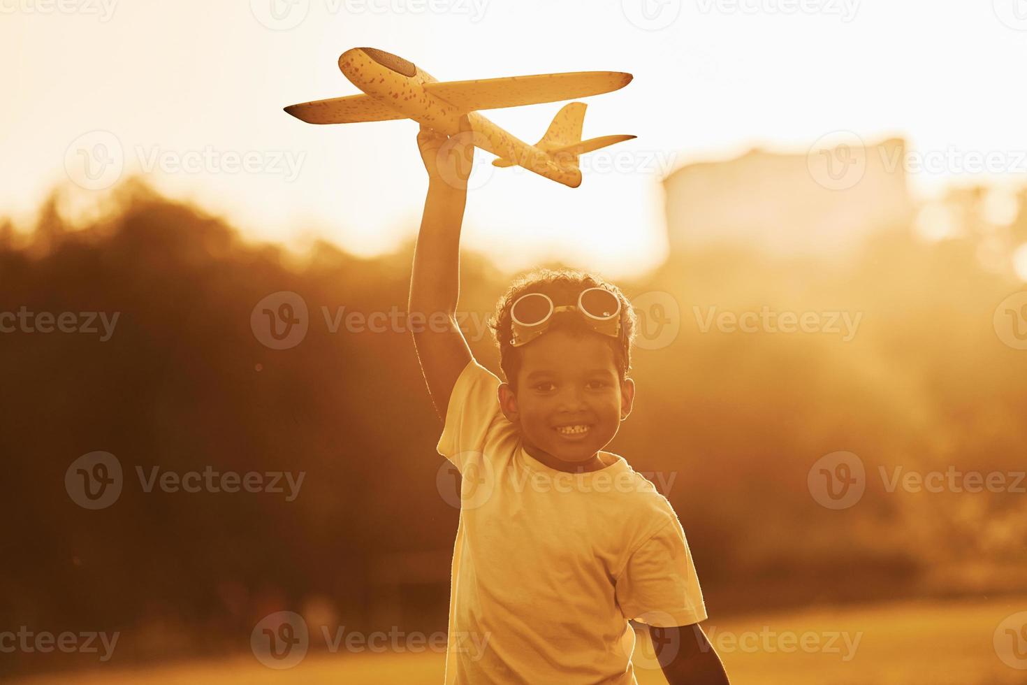 With pilot sunglasses. African american kid have fun in the field at summer daytime photo