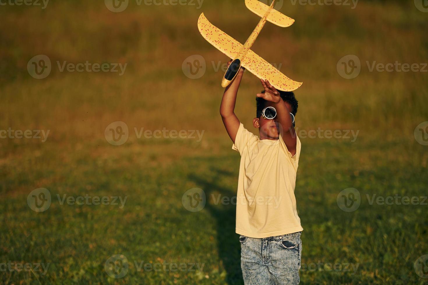 Retro style pilot sunglasses. African american kid have fun in the field at summer daytime photo