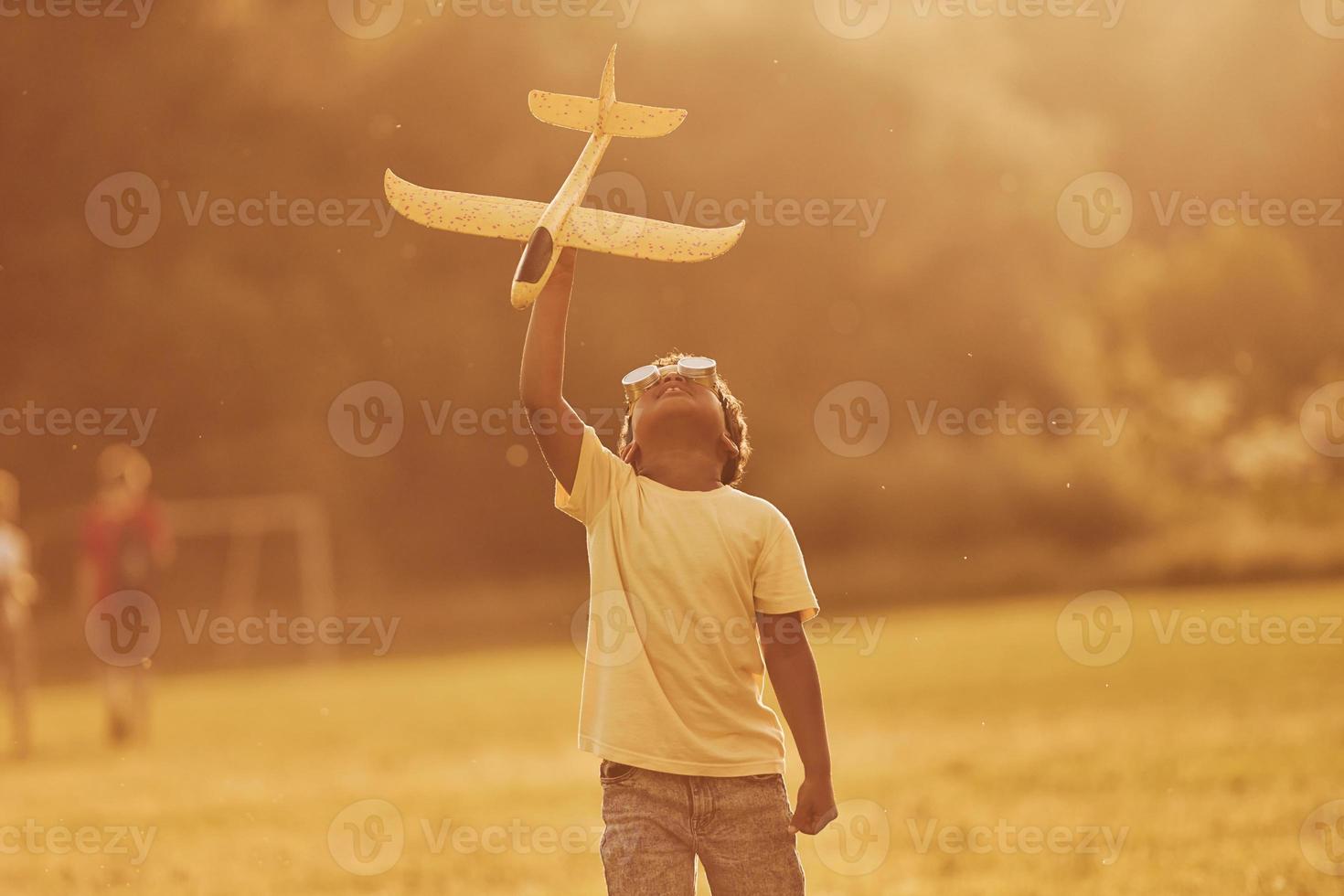 Power of imagination. Playing pilot game. African american kid have fun in the field at summer daytime photo