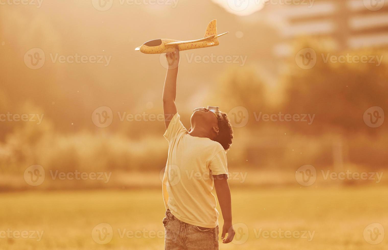Power of imagination. Playing pilot game. African american kid have fun in the field at summer daytime photo