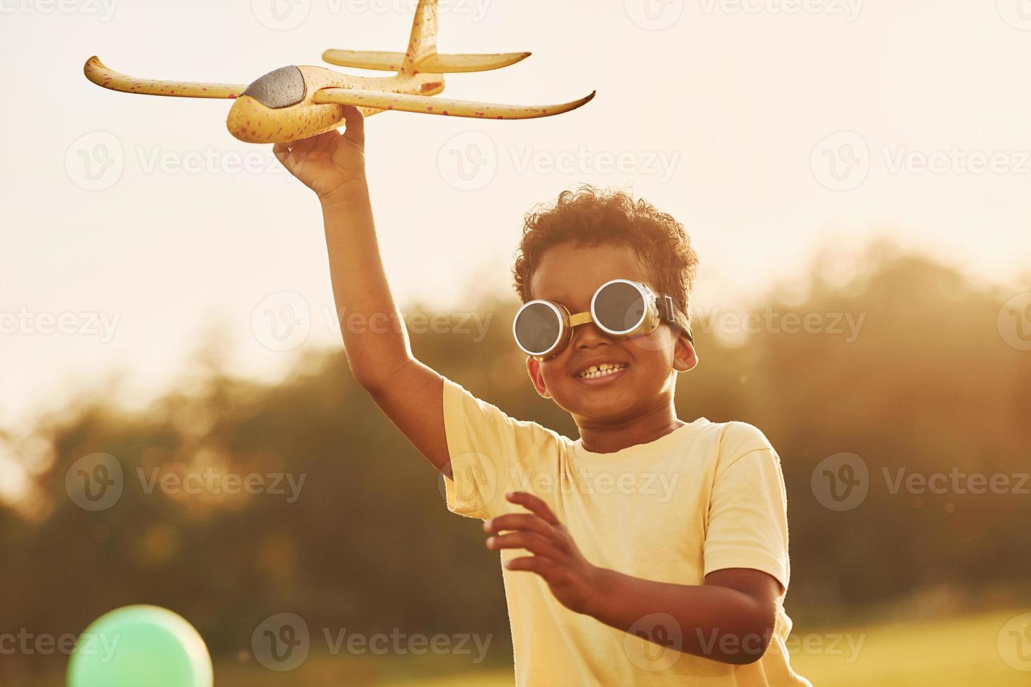 Power of imagination. Playing pilot game. African american kid have fun in the field at summer daytime photo