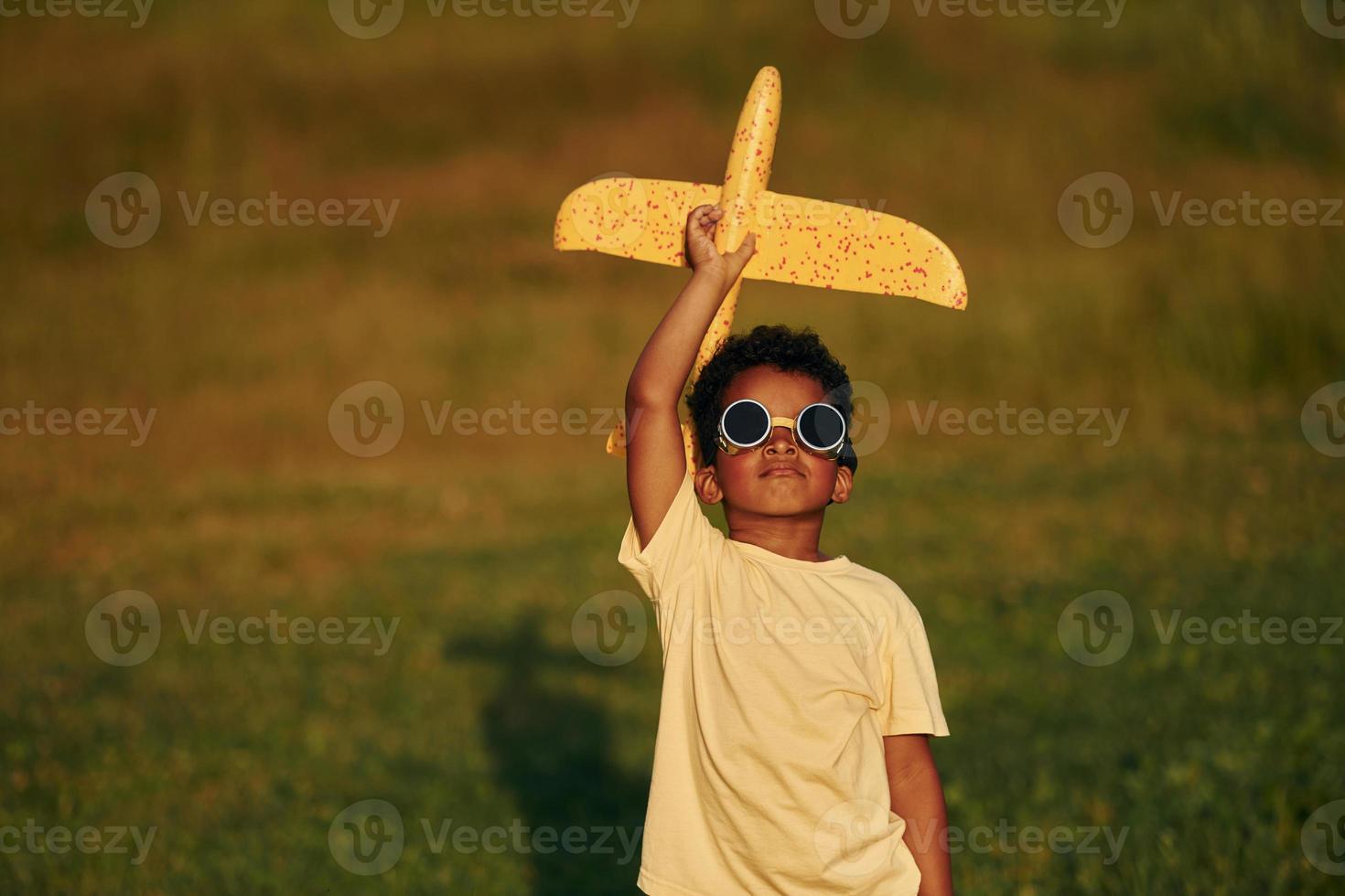 With pilot sunglasses. African american kid have fun in the field at summer daytime photo
