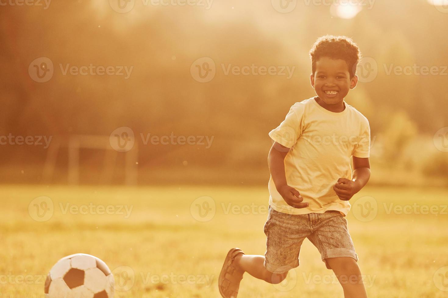 Active weekend time spending. African american kid have fun in the field at summer daytime photo