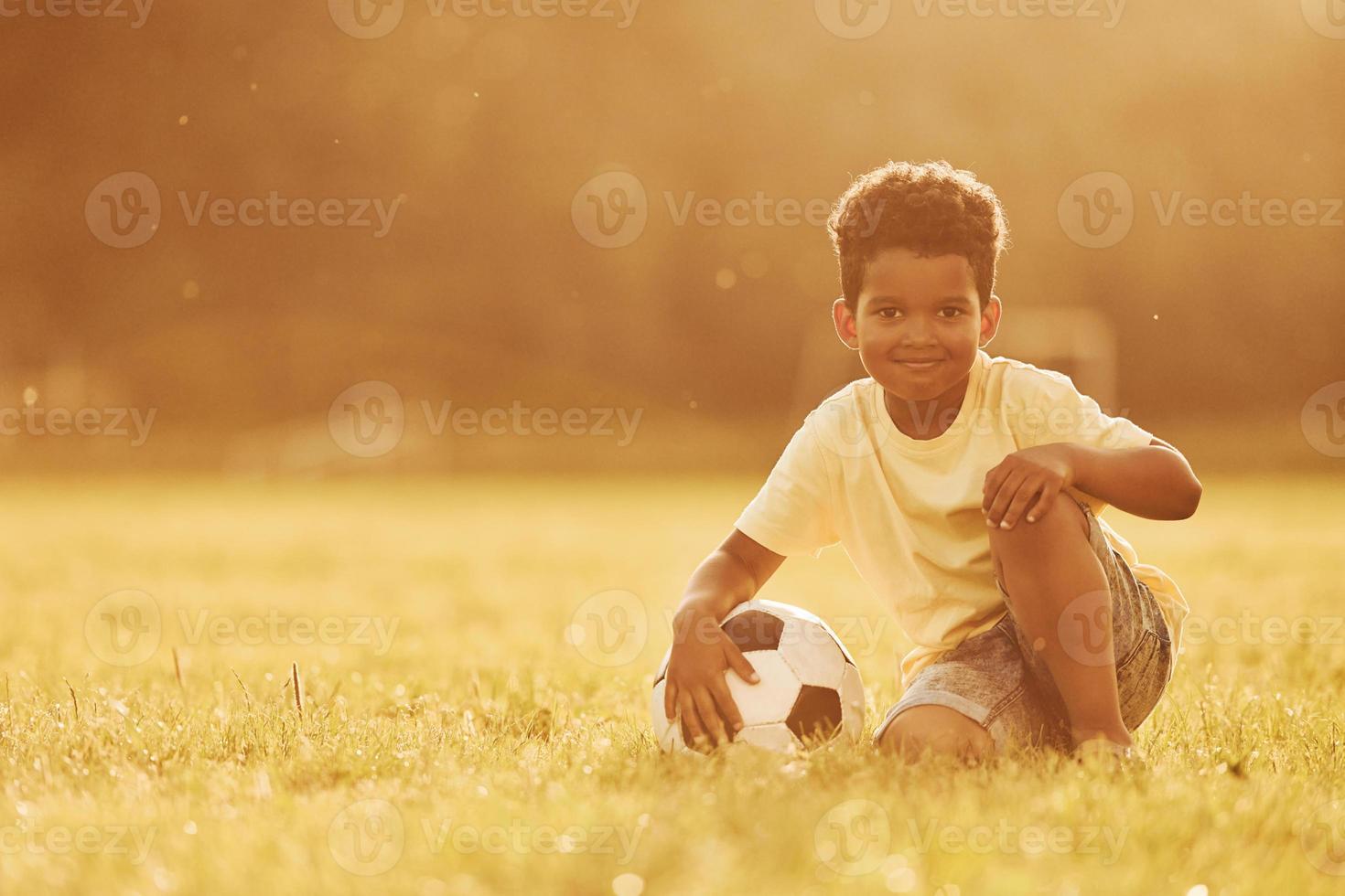 Illuminated by sunlight. African american kid have fun in the field at summer daytime photo