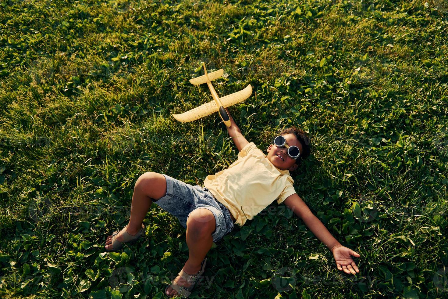 Beautiful summer daytime. African american kid have fun on the field photo