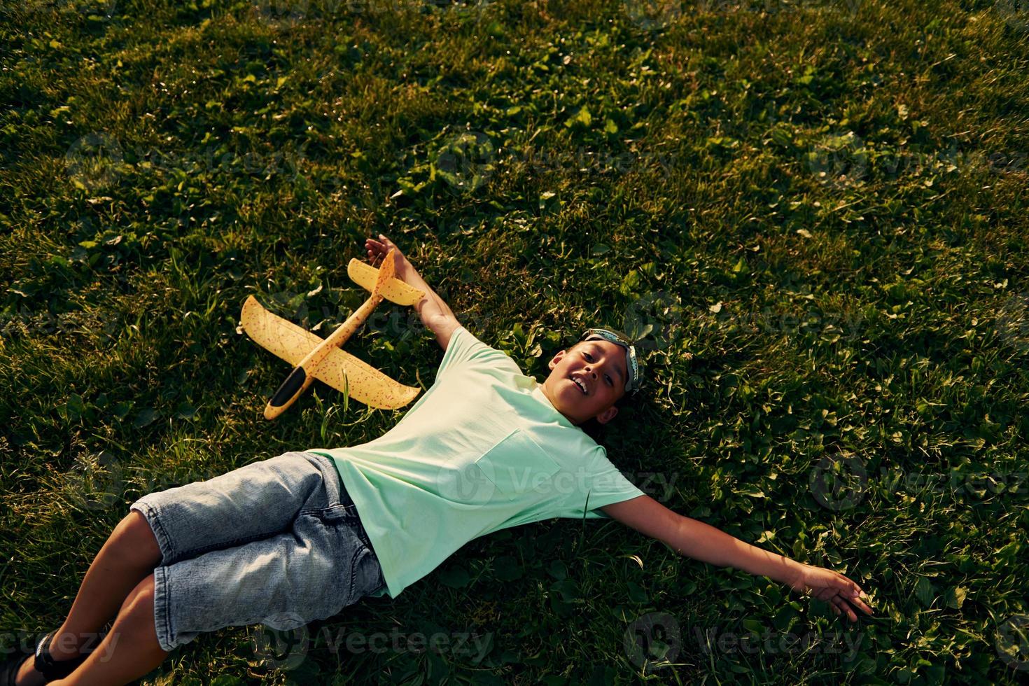 Resting on the ground. African american kid have fun in the field at summer daytime photo
