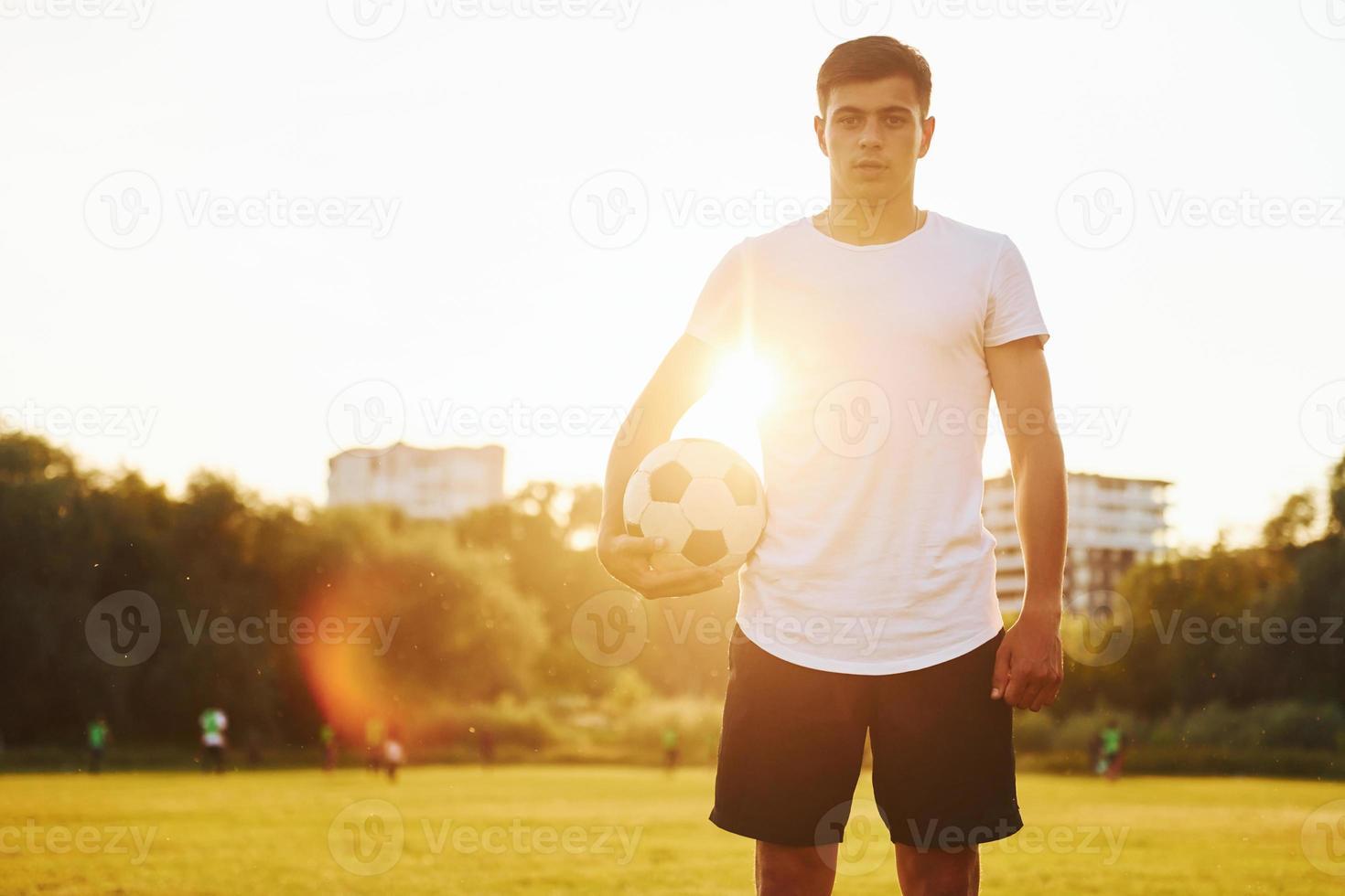 Standing and holding ball in hand. Young soccer player have training on the sportive field photo