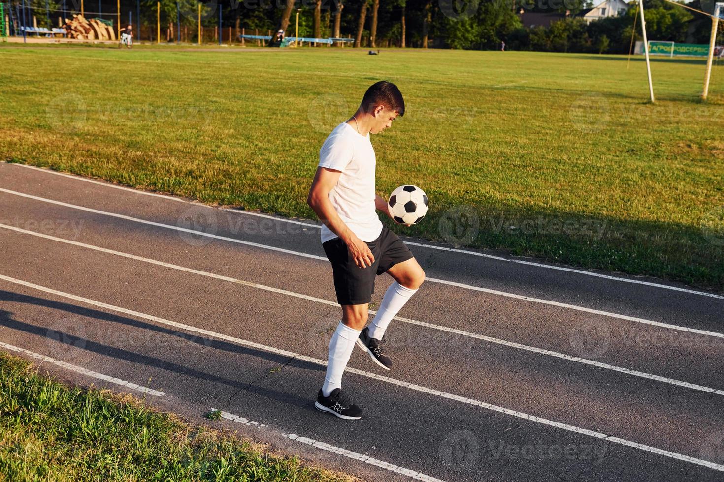 Holds ball in hand. Young soccer player have training on the sportive field photo