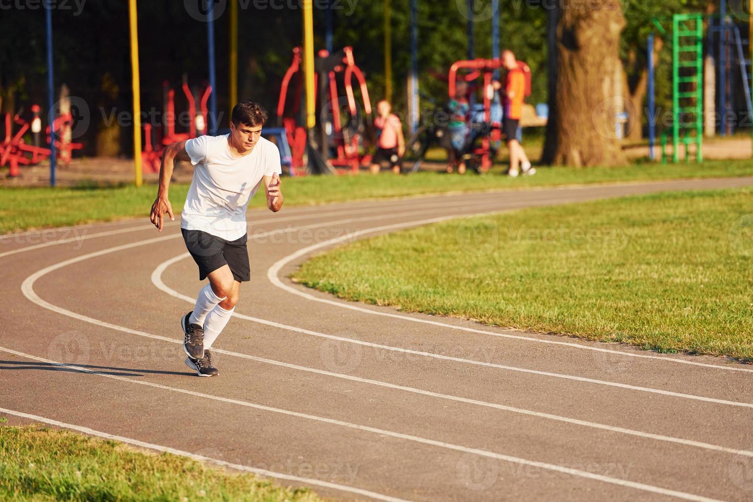 Man in sportive unifrom running on the track at daytime photo