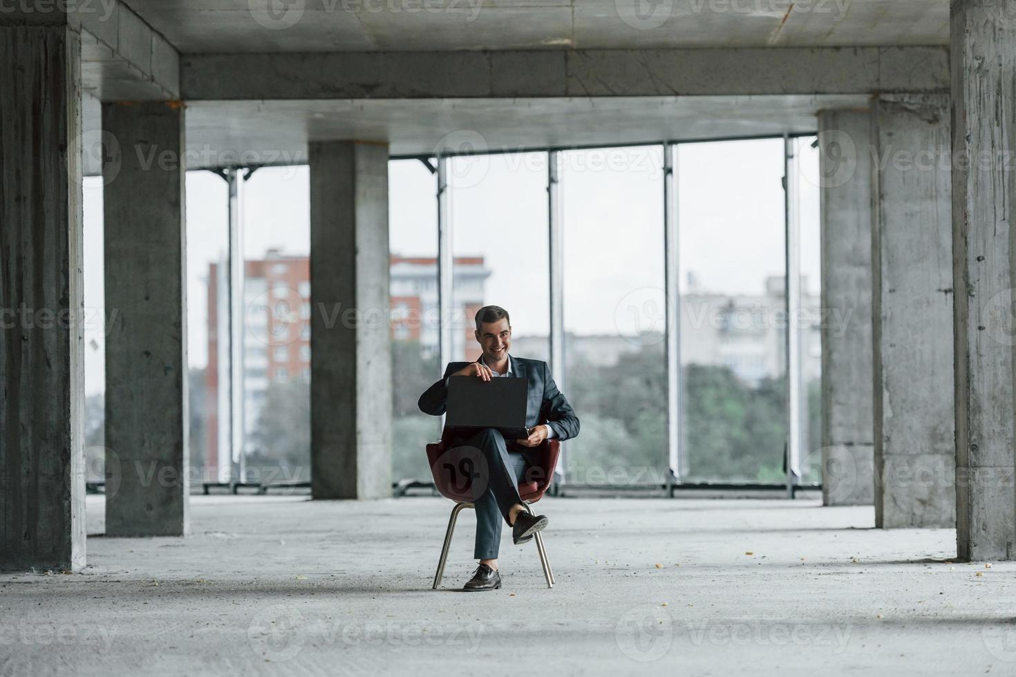 Businessman inside the building. Young man in formal wear is working indoors on the construction photo