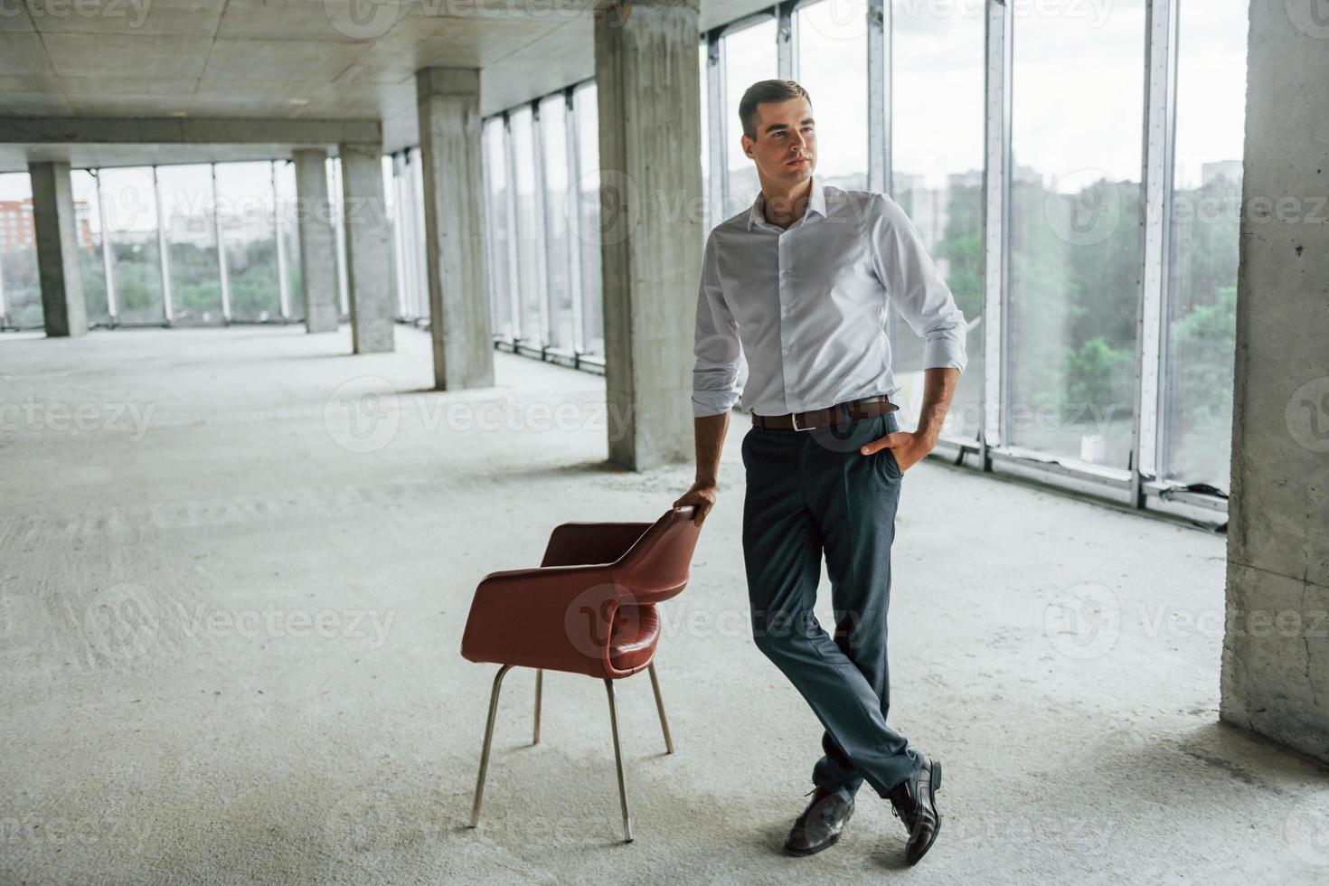 cerca de la silla. un joven con ropa formal está trabajando en el interior de la construcción foto